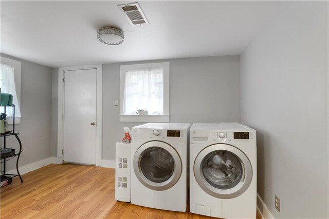 clothes washing area with laundry area, light wood finished floors, baseboards, visible vents, and separate washer and dryer