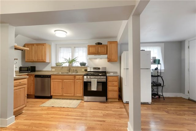 kitchen featuring appliances with stainless steel finishes, light wood-type flooring, light countertops, and under cabinet range hood