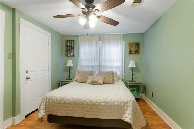 bedroom with a ceiling fan, baseboards, visible vents, and wood finished floors