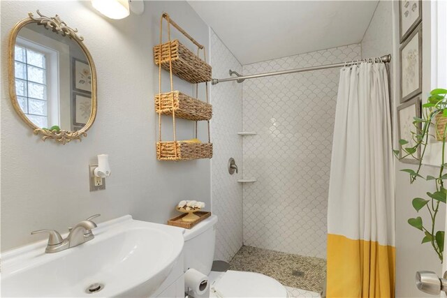 full bath with tiled shower, a sink, and toilet