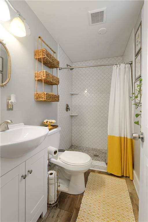 full bath featuring visible vents, a tile shower, and wood finished floors