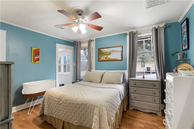 bedroom featuring ceiling fan, visible vents, baseboards, ornamental molding, and light wood finished floors