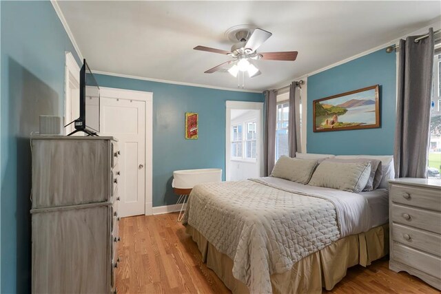 bedroom with a ceiling fan, light wood-style flooring, baseboards, and crown molding