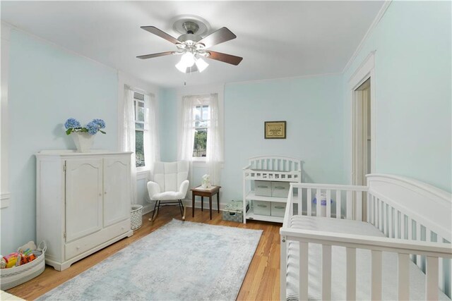 bedroom with a ceiling fan, crown molding, and light wood finished floors