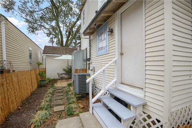 view of side of home with entry steps, fence, and cooling unit