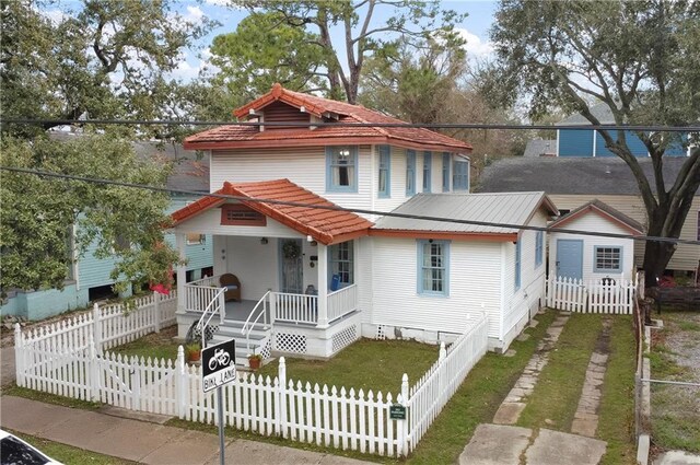 view of front of home with a fenced front yard, metal roof, covered porch, a gate, and a front yard