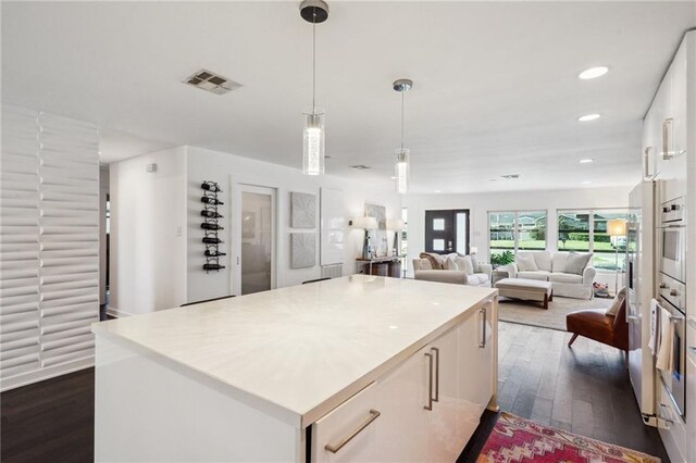 kitchen featuring dark wood-style flooring, visible vents, white cabinets, a kitchen island, and oven