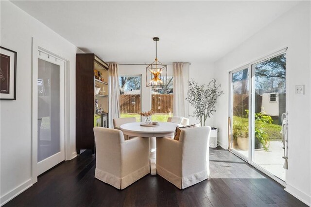 dining space featuring a notable chandelier, baseboards, dark wood-style flooring, and a wealth of natural light