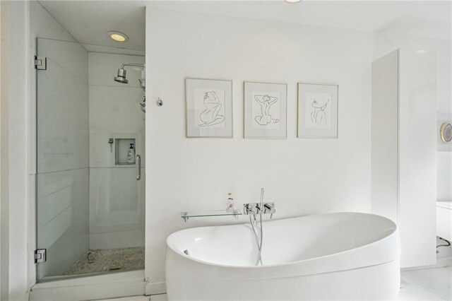 bathroom featuring recessed lighting, a freestanding bath, and a shower stall