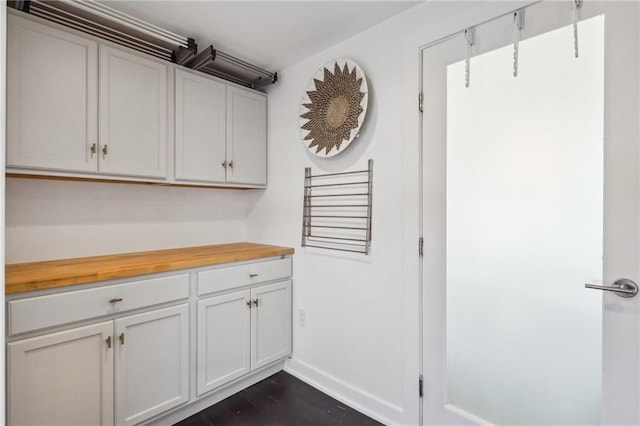 kitchen featuring butcher block counters, dark wood finished floors, and baseboards