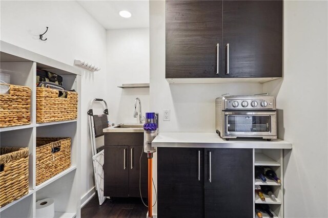 interior space featuring a sink, a toaster, open shelves, and dark wood-style flooring