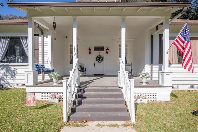 view of exterior entry featuring covered porch, a yard, and crawl space