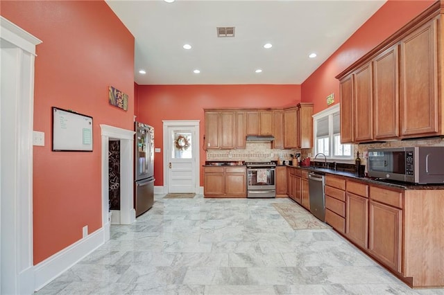 kitchen featuring visible vents, decorative backsplash, appliances with stainless steel finishes, a sink, and under cabinet range hood