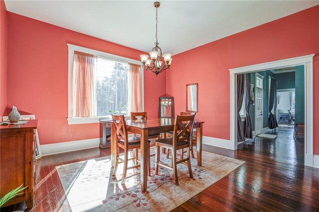 dining area featuring baseboards, hardwood / wood-style floors, and a notable chandelier