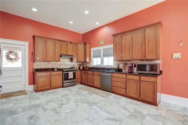 kitchen with appliances with stainless steel finishes, dark countertops, brown cabinets, and backsplash