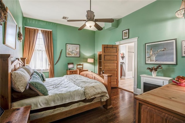 bedroom featuring ceiling fan, connected bathroom, visible vents, baseboards, and dark wood finished floors