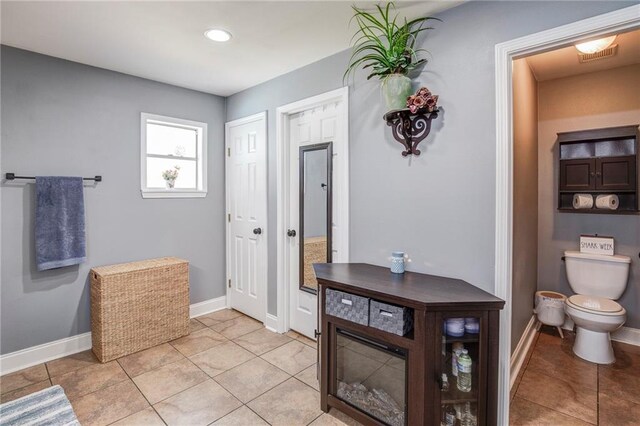 bathroom with tile patterned flooring, baseboards, visible vents, and toilet