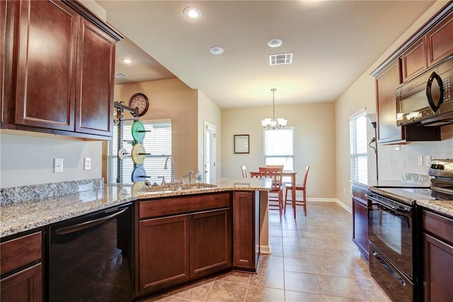 kitchen featuring visible vents, light stone counters, a peninsula, black appliances, and a sink