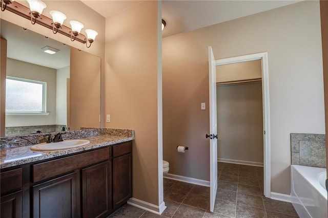 bathroom featuring vanity, a garden tub, toilet, and baseboards