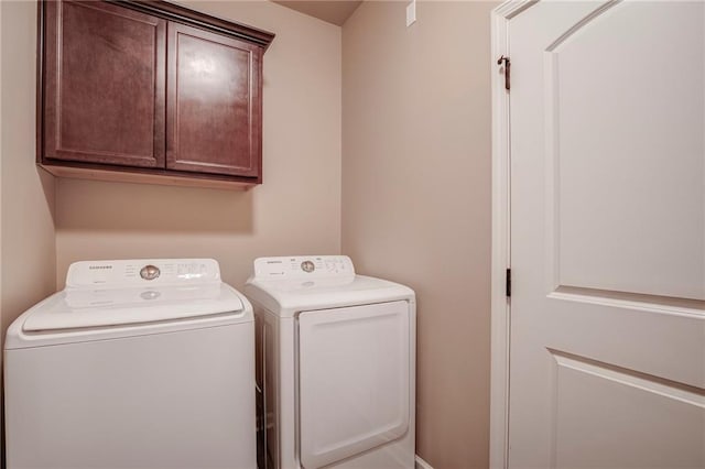 clothes washing area with washer and dryer and cabinet space