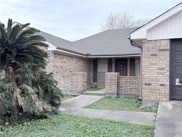 property entrance featuring a garage, brick siding, and roof with shingles