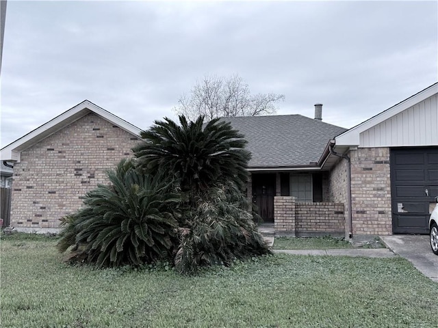 view of front of home with a front lawn, roof with shingles, an attached garage, and brick siding