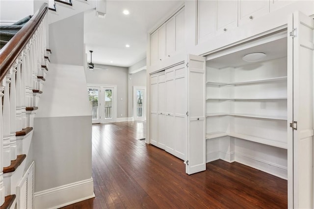 hallway featuring dark wood-style floors, stairs, baseboards, and recessed lighting