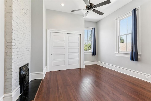 interior space with multiple windows, a fireplace, dark wood finished floors, and baseboards