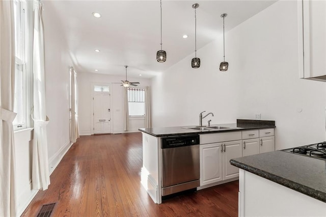 kitchen with dark countertops, a sink, and stainless steel dishwasher