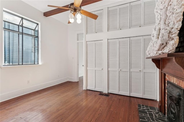 unfurnished bedroom with visible vents, a fireplace with flush hearth, a ceiling fan, wood finished floors, and baseboards