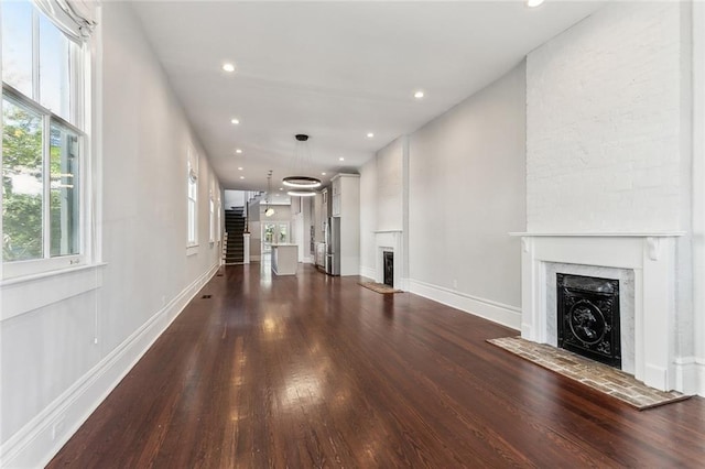 unfurnished living room featuring dark wood-type flooring, recessed lighting, a fireplace, and baseboards