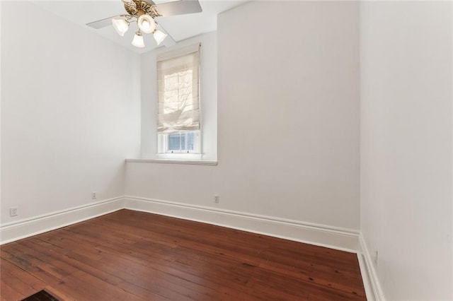 spare room with dark wood-style floors, baseboards, and a ceiling fan