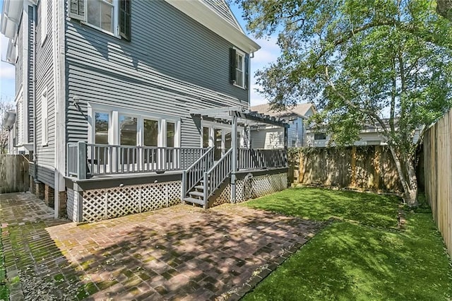 back of property with a fenced backyard, a yard, a wooden deck, a pergola, and a patio area