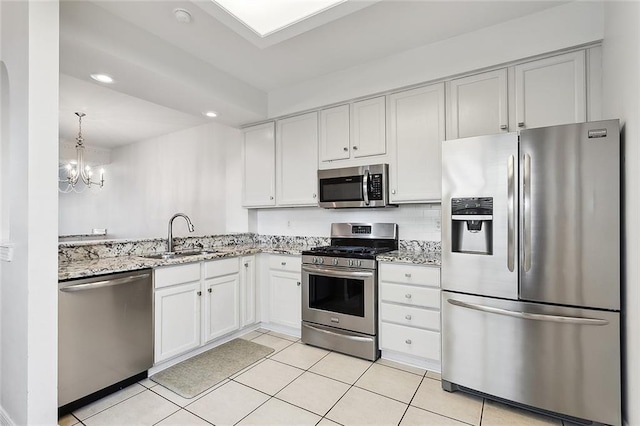 kitchen with light stone counters, light tile patterned flooring, recessed lighting, stainless steel appliances, and a sink