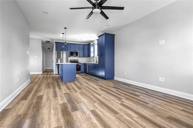 7909 Tarpon St, New Orleans, LA 70126 - kitchen featuring stainless steel appliances, blue cabinets, ceiling fan, light countertops, and a sink