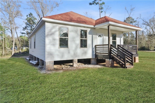 rear view of house featuring a shingled roof and a lawn