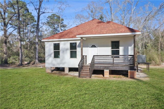 back of house featuring roof with shingles, a wooden deck, and a lawn
