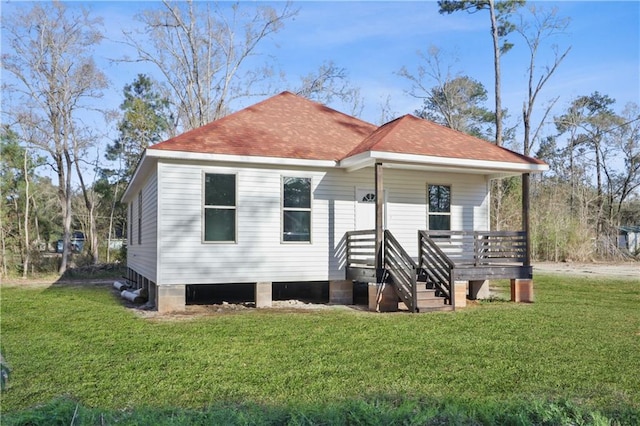 rear view of house featuring a porch, a yard, and roof with shingles