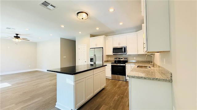 70378 C St, Covington, LA 70433 - kitchen featuring appliances with stainless steel finishes, light wood finished floors, a ceiling fan, white cabinets, and recessed lighting
