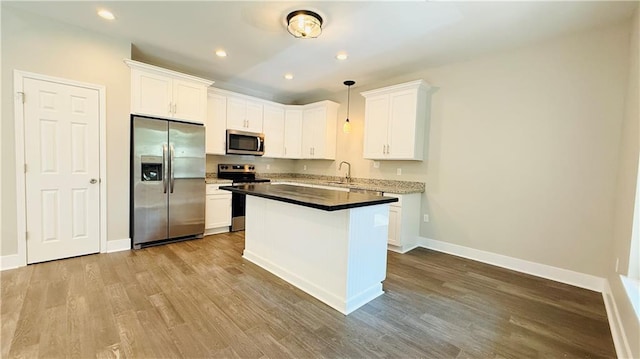 70378 C St, Covington, LA 70433 - kitchen featuring appliances with stainless steel finishes, white cabinetry, wood finished floors, a kitchen island, and recessed lighting