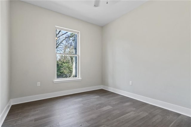 empty room with dark wood-type flooring and baseboards