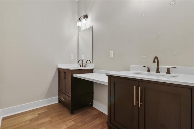 bathroom with two vanities, a sink, and wood finished floors