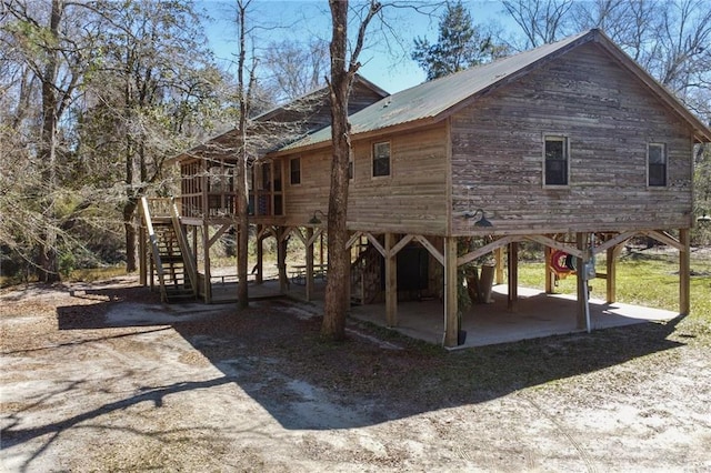 exterior space featuring stairs, metal roof, a patio, and a wooden deck