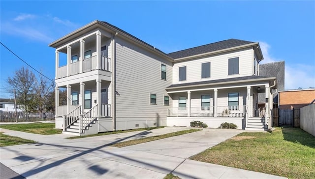 view of front of home with a porch, a front yard, fence, and a balcony