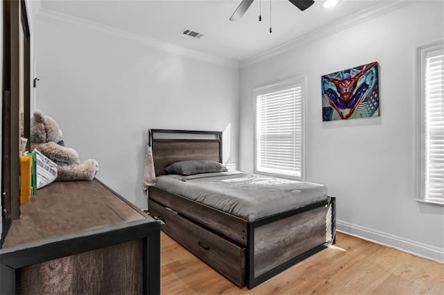 bedroom with light wood-style flooring, a ceiling fan, visible vents, baseboards, and ornamental molding