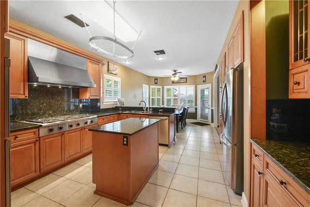 kitchen featuring light tile patterned floors, stainless steel appliances, visible vents, wall chimney range hood, and a peninsula