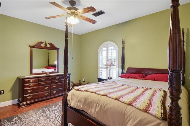 bedroom with a ceiling fan, baseboards, visible vents, and wood finished floors