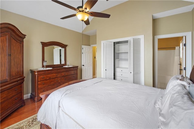 bedroom featuring vaulted ceiling, a closet, wood finished floors, and a ceiling fan