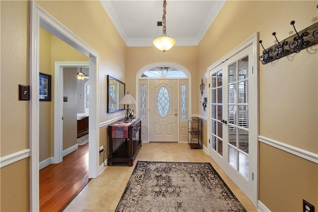 foyer entrance with french doors, crown molding, baseboards, and light tile patterned floors