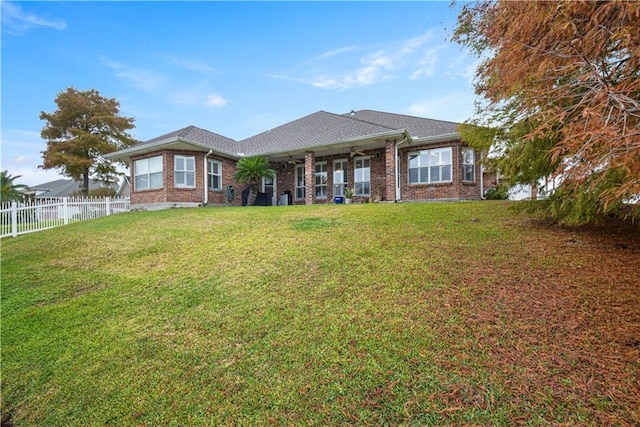 back of property with brick siding, ceiling fan, fence, and a yard